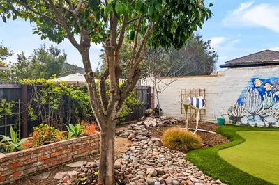a garden with a tree and a wall at Cozy Coastal Stay Hot Tub & Putting Green in San Diego