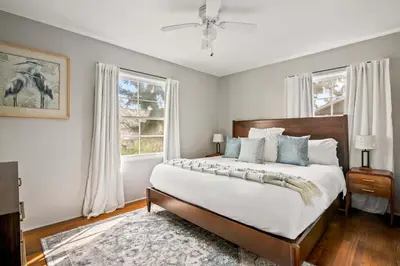 a bedroom with a large bed and two windows at Cozy Coastal Stay Hot Tub & Putting Green in San Diego