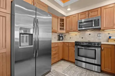 a stainless steel refrigerator in a kitchen with wooden cabinets at Sunglow Horizon - DMBC873B in Solana Beach