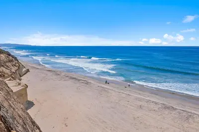 a beach with people walking on the sand and the ocean at Sunglow Horizon - DMBC873B in Solana Beach