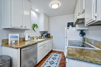 a kitchen with white cabinets and a sink and a refrigerator at 3080 Lincoln - Unit 12 in Carlsbad