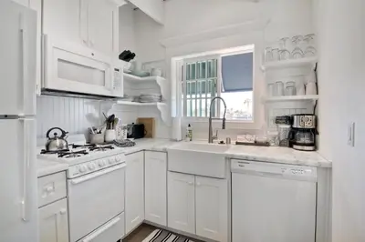 a white kitchen with white cabinets and a sink at 3690 Carlsbad Boulevard - Unit C in Carlsbad