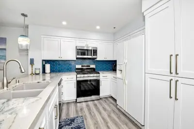 a white kitchen with white cabinets and a sink at 400 N Pacific - Unit 203 in Oceanside