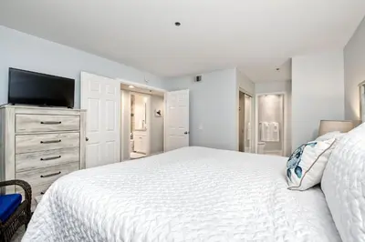 a white bedroom with a bed and a tv at 400 N Pacific - Unit 203 in Oceanside