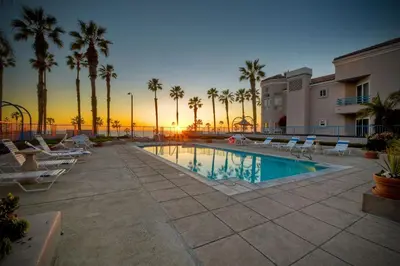 a pool with chairs and palm trees at sunset at 400 N Pacific - Unit 203 in Oceanside