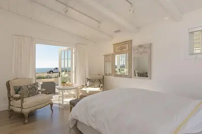 a white bedroom with a bed and a view of the ocean at 3690 Carlsbad Boulevard - Unit A in Carlsbad