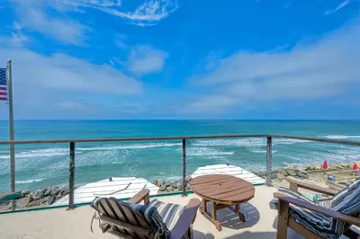 a balcony with chairs and a table and the ocean at 1745 S Pacific in Oceanside