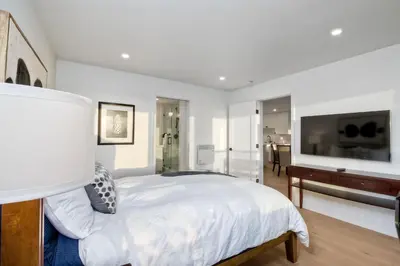 a white bedroom with a bed and a television at 597 S Sierra Avenue - Unit 68 in Solana Beach