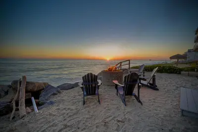two chairs and a table on the beach with the sunset at 1409 S Pacific Street 5BR in Oceanside