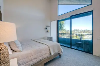 a bedroom with a bed and a balcony with a view at 916 Sea Lane in Encinitas