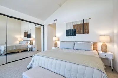a white bedroom with a bed and a mirror at 916 Sea Lane in Encinitas