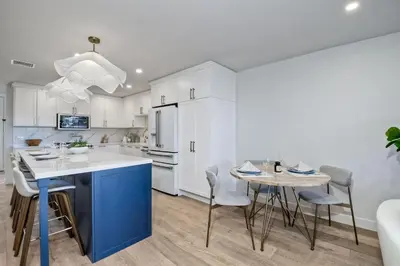 a kitchen with white cabinets and a blue island and a table at 916 Sea Lane in Encinitas