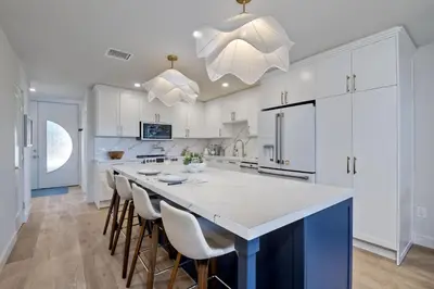a kitchen with white cabinets and a large island with bar chairs at 916 Sea Lane in Encinitas
