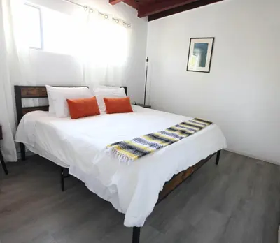 a bedroom with a large white bed with orange pillows at West Coast Surf and Stay in San Clemente