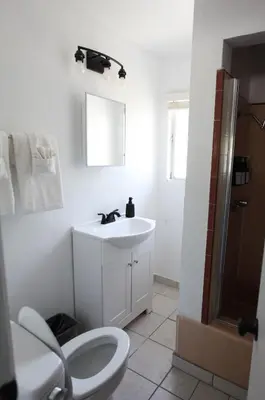 a white bathroom with a toilet and a sink at West Coast Surf and Stay in San Clemente
