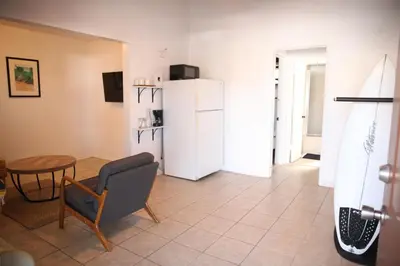 a living room with a refrigerator and a table at West Coast Surf and Stay in San Clemente