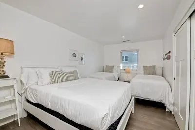 a white bedroom with two beds and a window at 3636 Carlsbad Blvd - Upper in Carlsbad