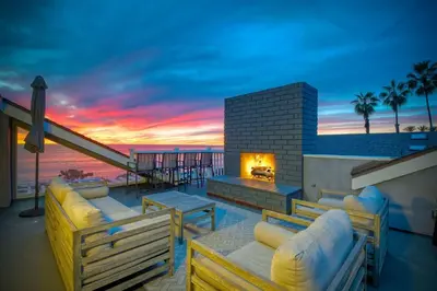 a patio with couches and a fireplace with a sunset at 3636 Carlsbad Blvd - Upper in Carlsbad