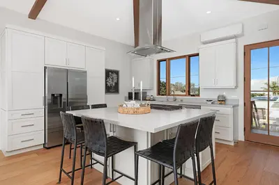 a kitchen with a large white island with black chairs at 5194 Carlsbad - Upper in Carlsbad