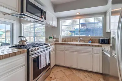 a kitchen with white cabinets and a stove top oven at Steps to ocean & bay large patio 4 parking spots in San Diego