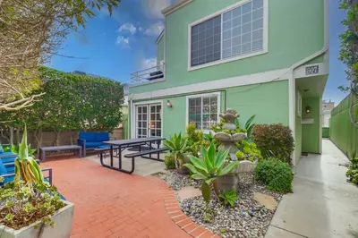 a green house with a patio in front of it at Steps to ocean & bay large patio 4 parking spots in San Diego
