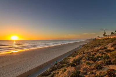 a beach at sunset with the sun setting over the ocean at 165 n 167 Tamarack in Carlsbad