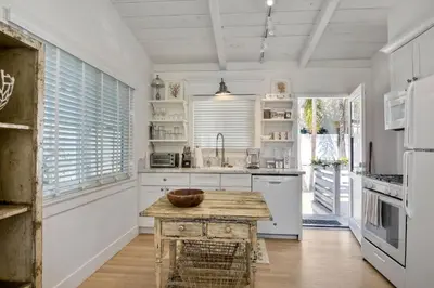 a kitchen with white cabinets and a wooden table at 180 n 190 Walnut Entire Home in Carlsbad