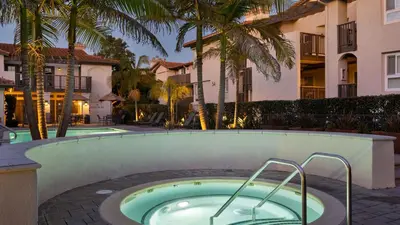a hot tub in front of a building with palm trees at Walk to Beach Pool Hot Tub Private Patio Parking Seabreeze Retreat in Dana Point