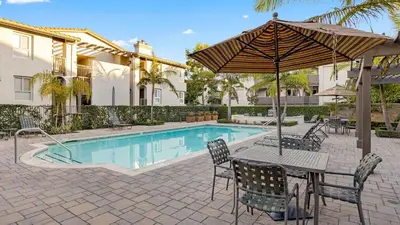 a table with an umbrella next to a swimming pool at Walk to Beach Pool Hot Tub Private Patio Parking Seabreeze Retreat in Dana Point