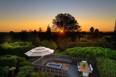 an umbrella and chairs on a deck with the sunset at 327 Hillcrest Drive in Encinitas