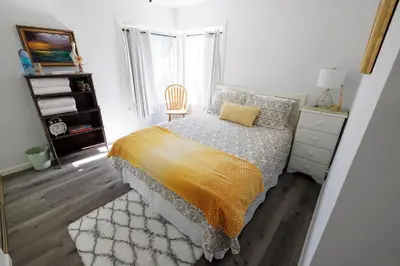 a white bedroom with a bed and a chair at Family fun near the beach-sold in Oceanside