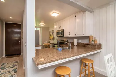 a kitchen with white cabinets and a counter with stools at Walk to the Beach Balcony Sunset Ocean Views in Oceanside
