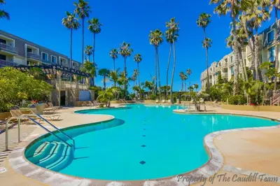 a swimming pool in a resort with palm trees at Walk to the Beach Balcony Sunset Ocean Views in Oceanside