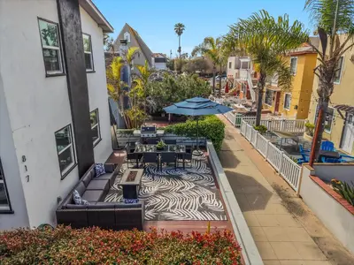 an outdoor patio with tables and chairs and umbrellas at Steps to the Beach with Private Patio BBQ and Fire Pit in San Diego
