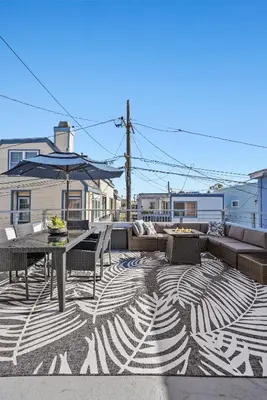 a patio with a table and a couch and an umbrella at Mission Beach Escape Near Ocean and Bay with Private Balcony BBQ and Garage Parking in San Diego