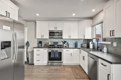 a kitchen with white cabinets and a stainless steel refrigerator at Mission Beach Escape Near Ocean and Bay with Private Balcony BBQ and Garage Parking in San Diego