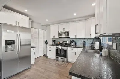 a kitchen with white cabinets and a stainless steel refrigerator at Mission Beach Escape Near Ocean and Bay with Private Balcony BBQ and Garage Parking in San Diego