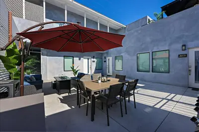 a patio with a wooden table and a red umbrella at Harborside Suite 10 with Hot Tub and King Bed in San Diego