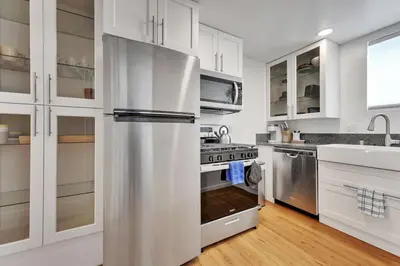 a kitchen with white cabinets and a stainless steel refrigerator at Harborside Suite 06 with Hot Tub and King Beds in San Diego