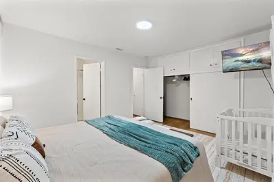 a white bedroom with a bed and a crib at Entire Private Home with 4 Bedrooms 2 Bathrooms, Spacious, Lux King Bed, Ranch Style, Prime Area, Available Now in La Mesa