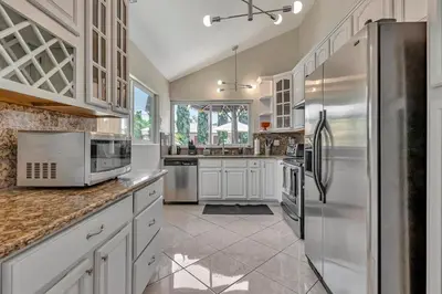 a kitchen with white cabinets and a stainless steel refrigerator at Tropical Bliss - 5BR Pool Spa Games 12 min to dwtn in San Diego