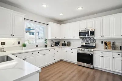a kitchen with white cabinets and a black stove top oven at Carroll Family Retreat in San Jacinto