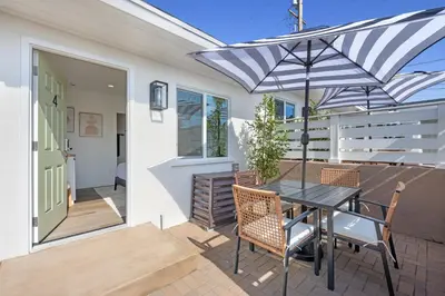 a patio with a table and chairs and an umbrella at South O Bungalow 4 - Deluxe Queen Studio + Patio in Oceanside