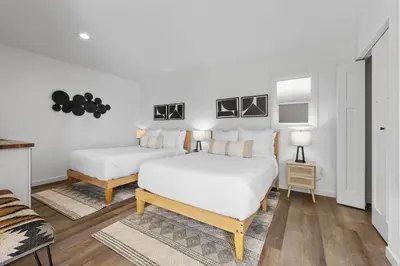 two beds in a room with white walls and wooden floors at South O Bungalow 7 - Premium Double Studio + Patio in Oceanside