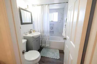 a white bathroom with a toilet and a sink at Near SoCal sports complex, Frontwave Arena-Sold in Oceanside