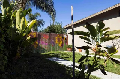 a fence with graffiti on it next to a house at Near SoCal sports complex, Frontwave Arena-Sold in Oceanside