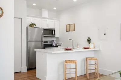 a kitchen with a refrigerator and a counter with stools at The Little Oasis in Escondido