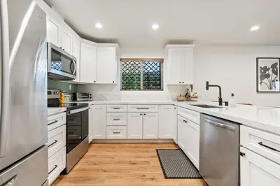 a kitchen with white cabinets and a stainless steel refrigerator at The Oasis in Escondido
