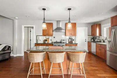 a kitchen with wooden cabinets and a island with bar stools at Cozy 3BR Steps to Dining & Attractions in San Diego