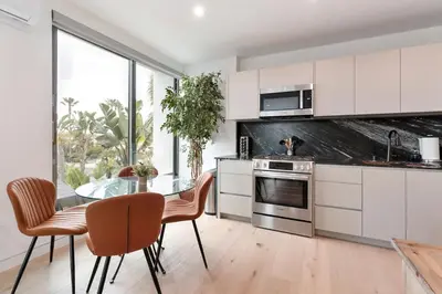 a kitchen with white cabinets and a glass table and chairs at Ocean View Luxury Living in Carlsbad